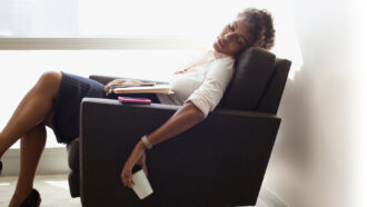 a person nodding off in a chair, holding a cup over the side