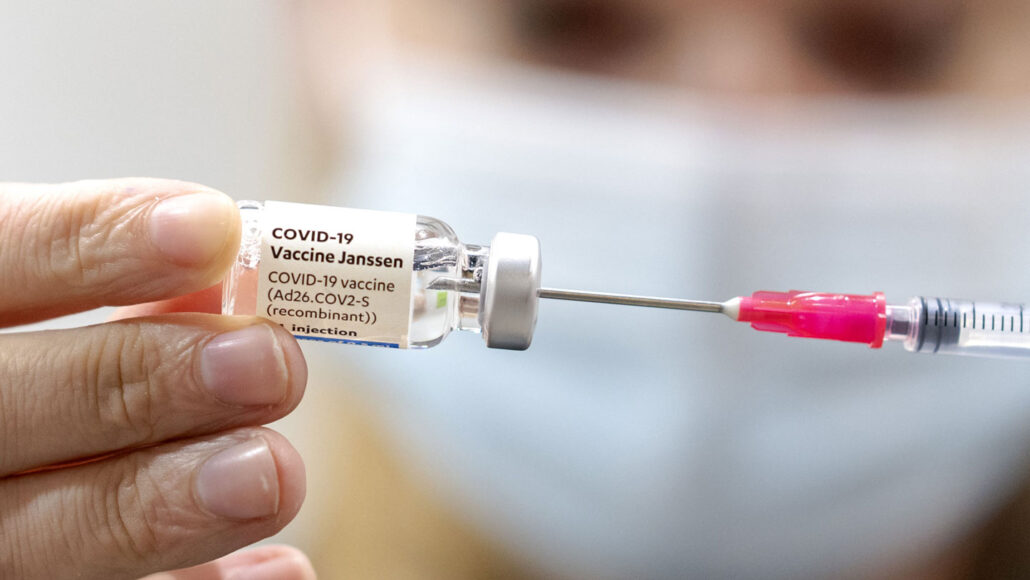 photo of someone holding a vial of the J&J covid vaccine with a syringe