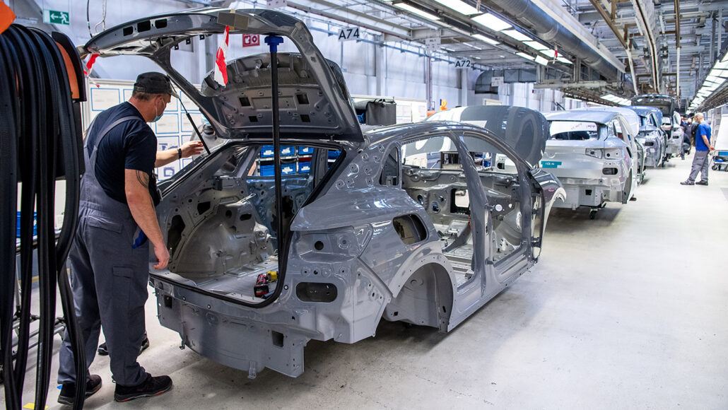 a photo of workers in an automobile factory working on electric vehicles