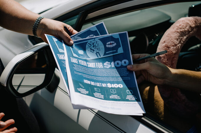 a person hands pamphlets to a person in a car