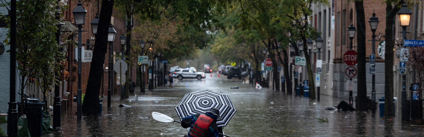 a kayaker paddles down a street as it rains in Old Town Alexandria, Virginia