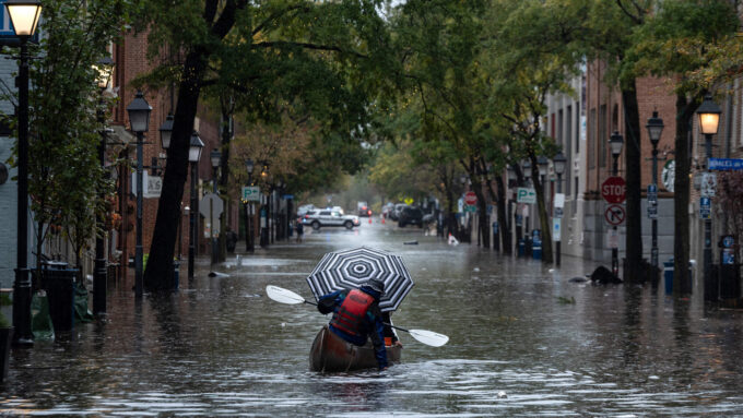 a kayaker paddles down a street as it rains in Old Town Alexandria, Virginia