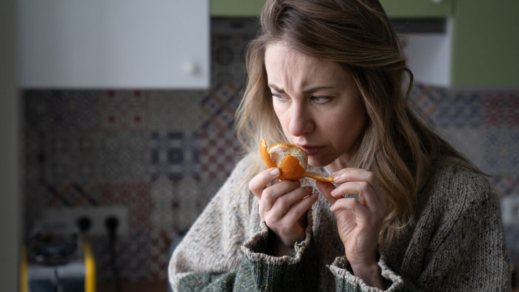 image of a woman smelling an orange