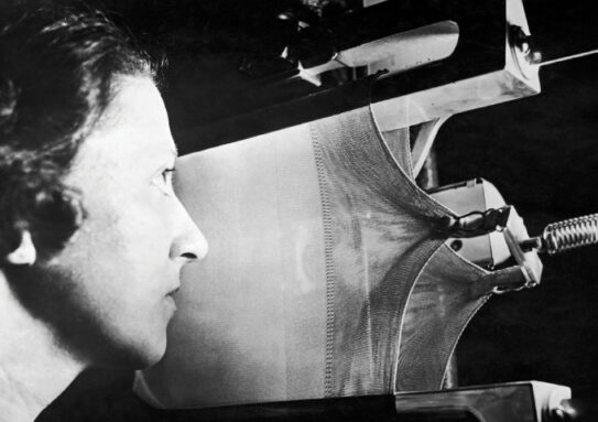 black and white image of a woman observing a test of nylon strength