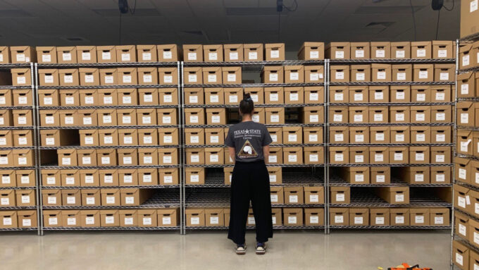 scientist facing a rack of boxes of skeletal remains