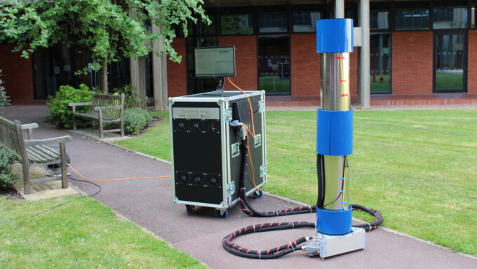 a quantum gravity sensor comprised of a black box connected to a cylinder sits on a sidewalk