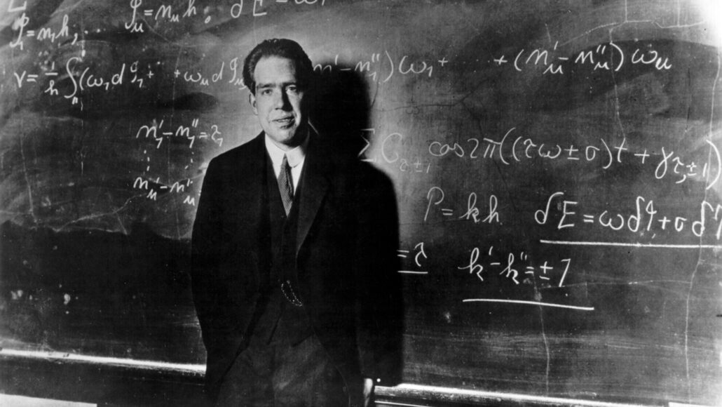 black and white image of Niels Bohr standing in front of a chalkboard