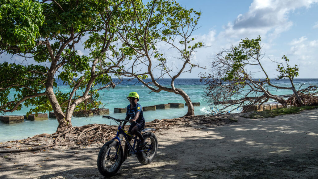 photo of a child riding a bike near the shoreline in the Maldives
