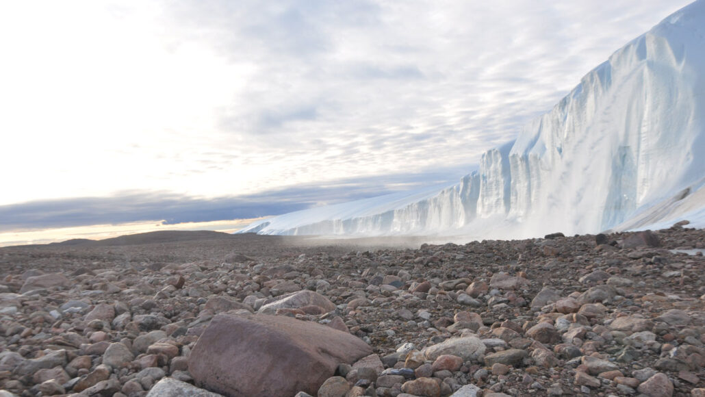 pebbles in the foreground with Greenland's ice sheet in the background