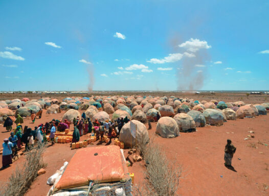 photo of people lining up for water amid tents in a makeshift camp for families displaced by drought