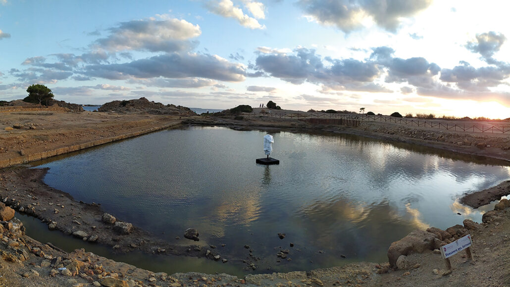 photo of the Phoenician pool with a white statue of Ba’al in the center and the ocean in the distance