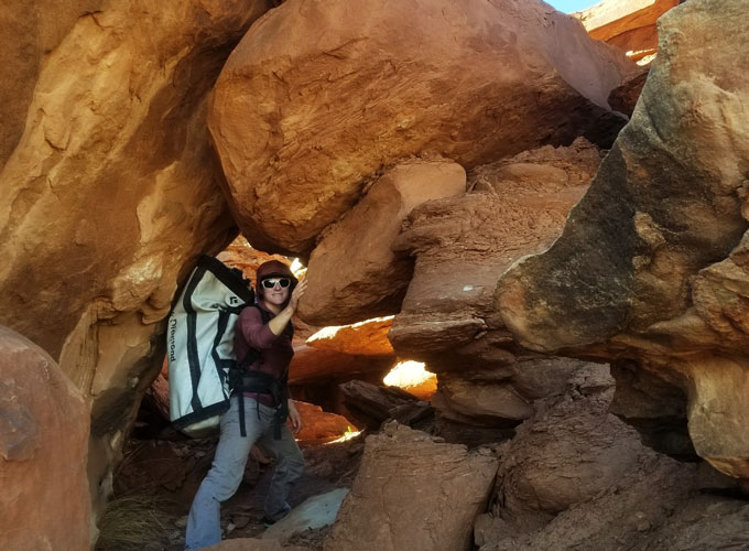 Kathryn Vollinger carries equipment through red rock formations