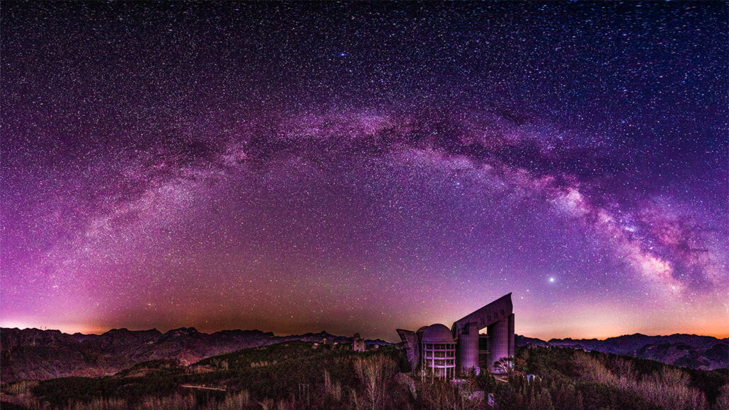 photo of the Milky Way with purple hues in the sky above the Large Sky Area Multi-Object Fiber Spectroscopic Telescope in China