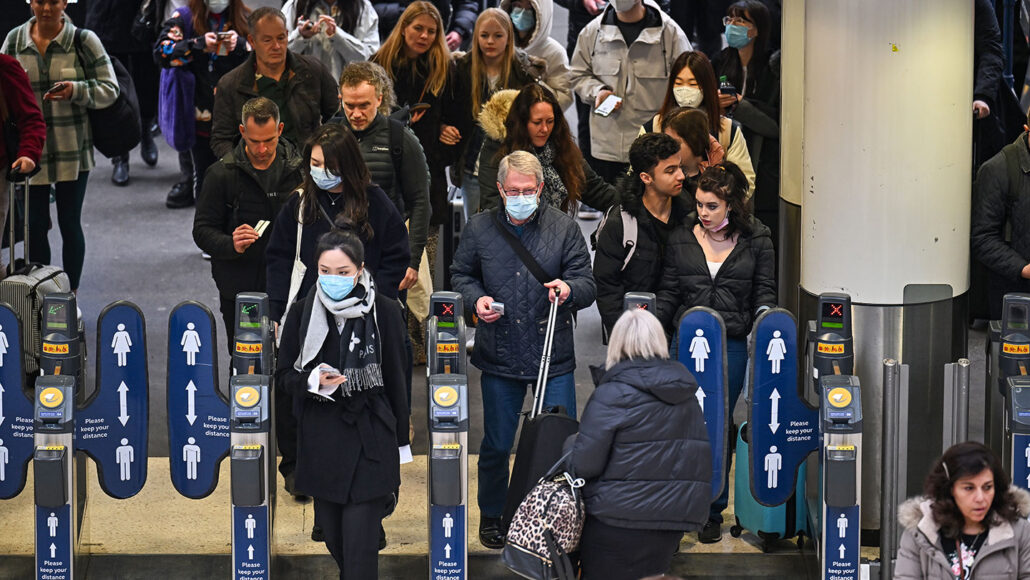 photo of commuters, some masked, some unmasked at Waterloo station in London