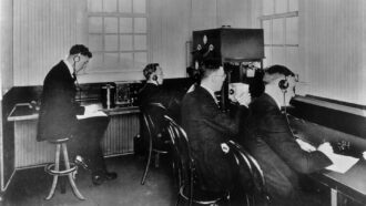 historical photo of a 1920s radio broadcast station with men wearing headphones