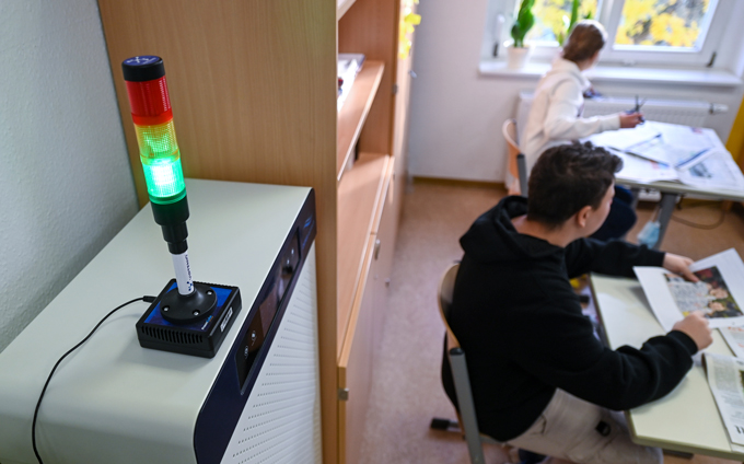 photo of a carbon dioxide light with green, yellow and red hues in the foreground and students seated at desks in the background