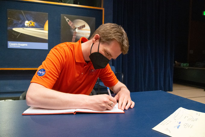 Håvard Fjær Grip seated at a table, signing the logbook
