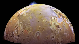 a blue burst of light from a volcanic eruption can be seen on the surface of Io