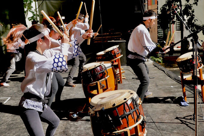 a group of Brazilian Japanese youths play taiko drums on a stage