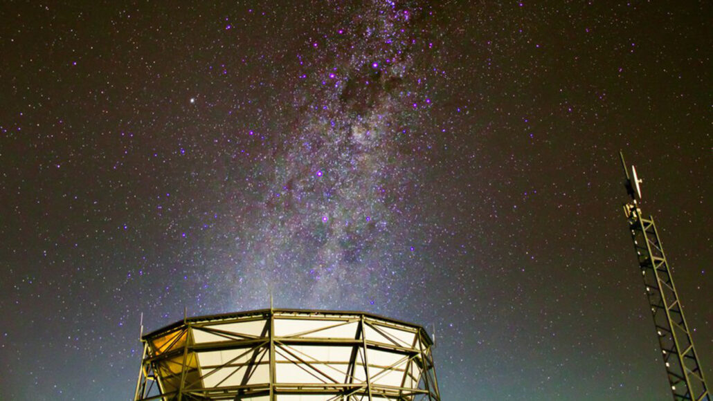 a photo of the Atacama Cosmology Telescope scanning the night sky with the Milky Way overhead
