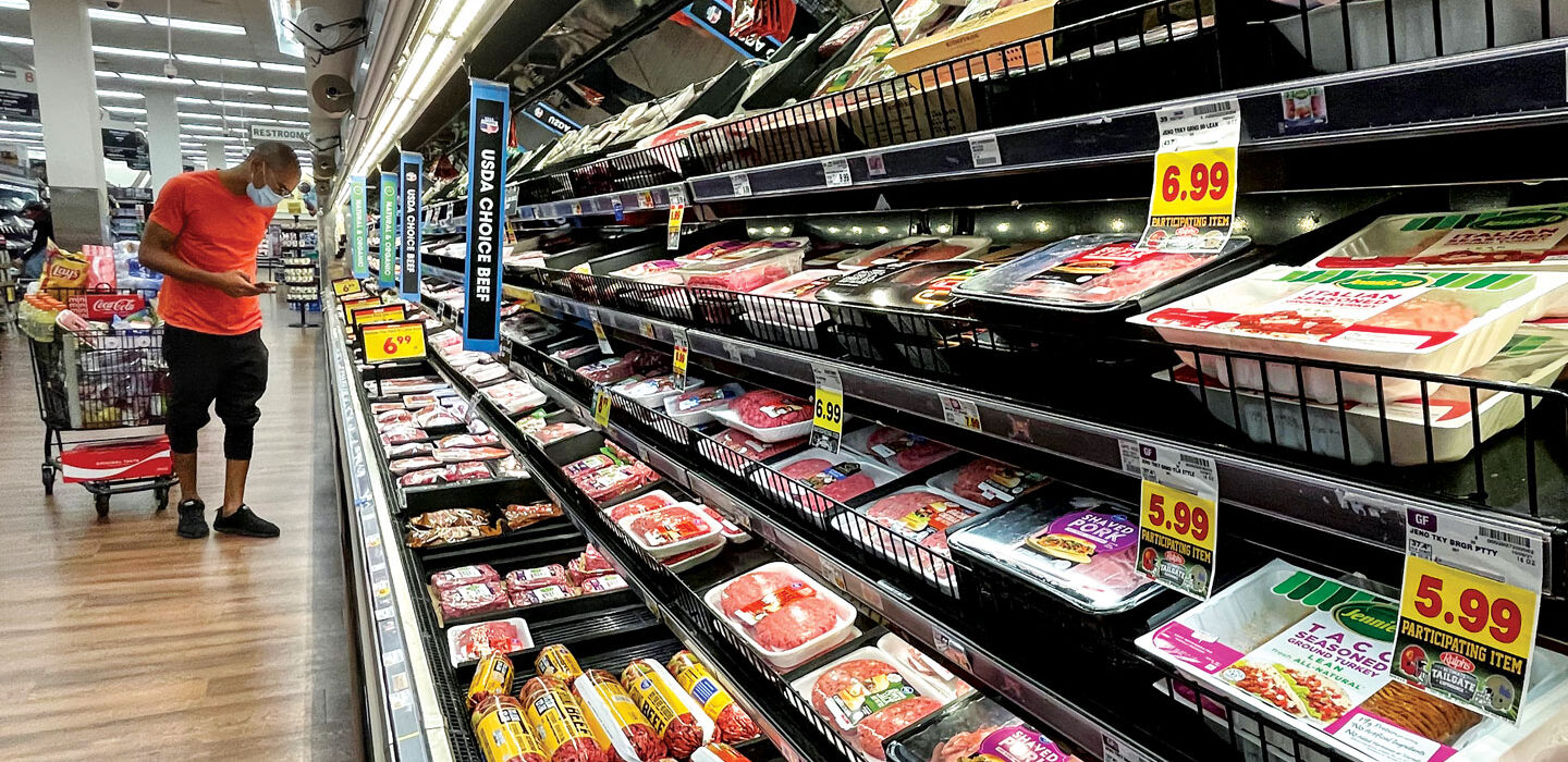 a customer surveys the meat section in a grocery store