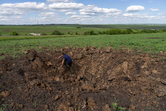 a person climbs out of a crater in a grassy field