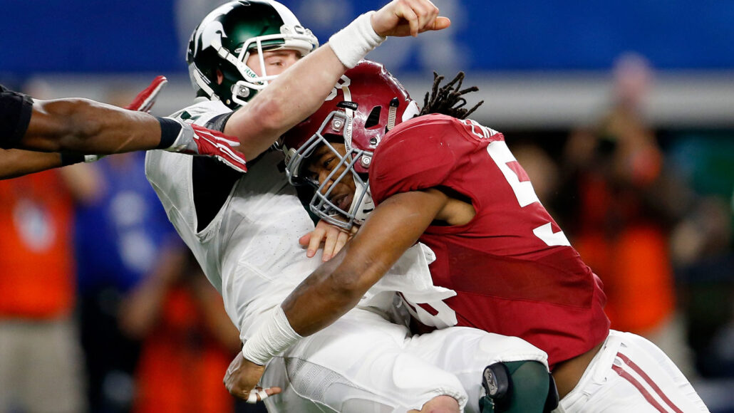a football player tackles a quarterback during the 2015 Goodyear Cotton Bowl