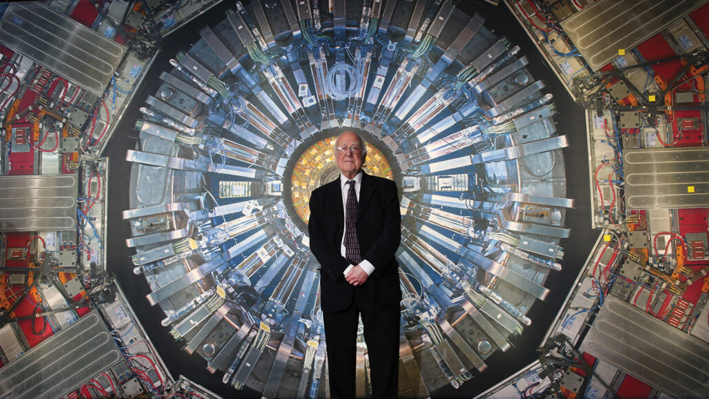 Peter Higgs in front of a photo of a detector at the Large Hadron Collider