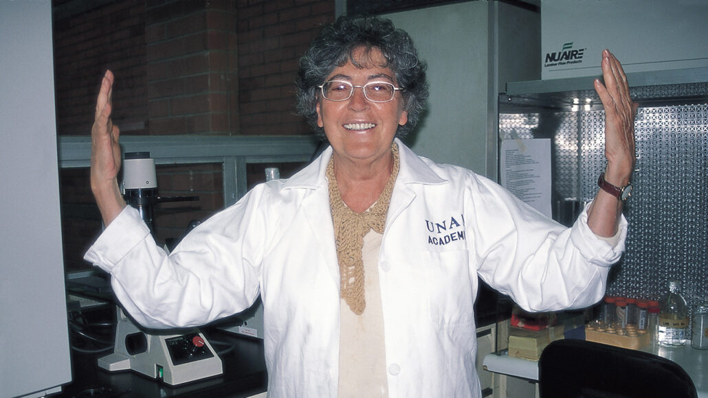Herminia Pasantes stands in her lab with her arms raised in excitement