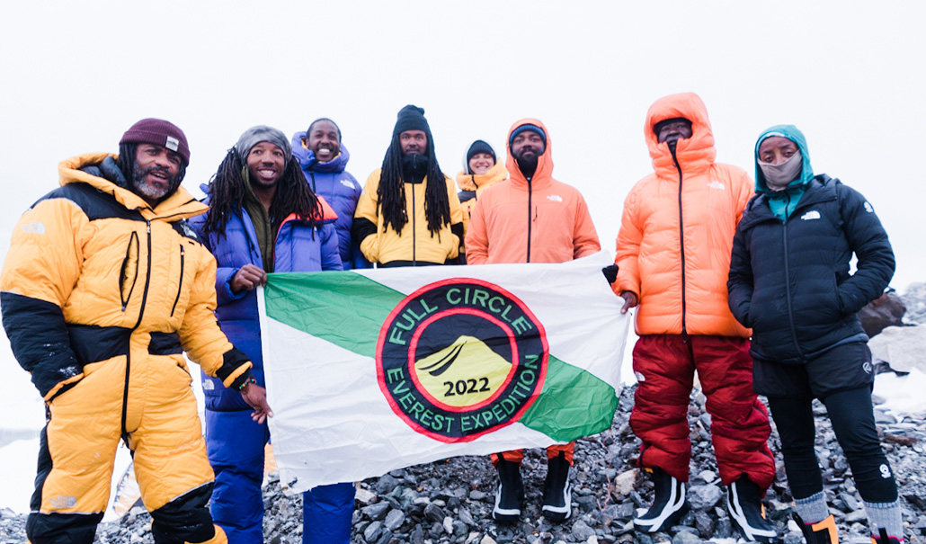 a photo of eight beaming Full Circle mountaineers smiling and holding a 2022 Full Circle Everest Expedition banner