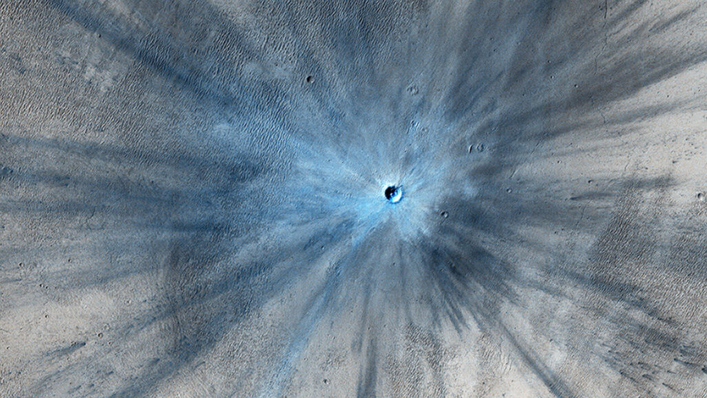 Glassy debris creates the bluish tinge and radiating black stripes around an impact crater on Mars
