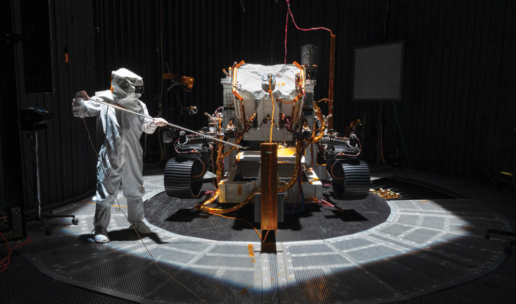 image of an engineer working on the Perseverance rover in a clean room with light from above