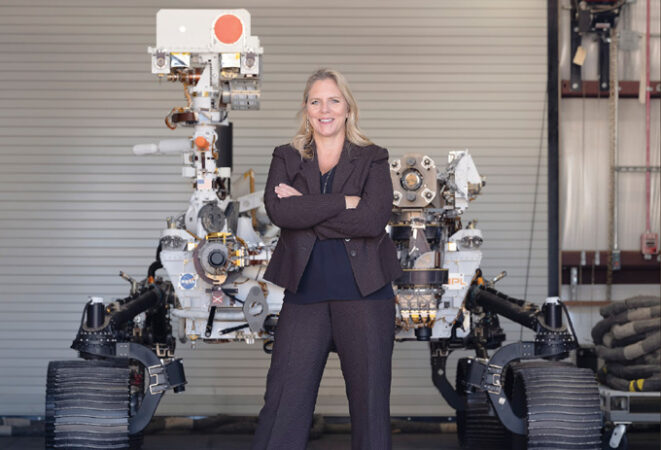 image of Jennifer Trosper standing in front of a model of the Perseverance rover
