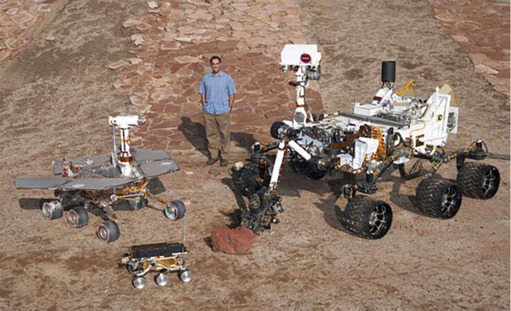 Ashwin Vasavada stands amid models of various NASA Mars rovers
