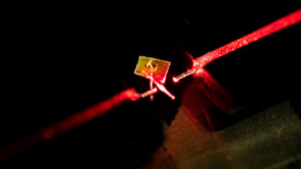 photo of a levitating force sensor in gold amid red-hued light