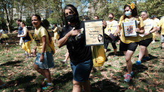 a woman holds of a lost loved one at the second annual COVID March to Remember