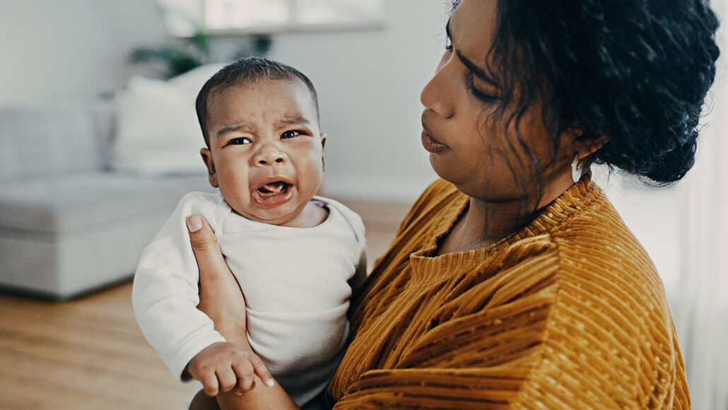 photo of a woman holding and trying to settle a crying baby