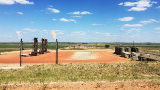 photo of natural gas flares in the foreground at the Bakken Formation in the Williston Basin in North Dakota in 2021