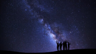 five people silhouetted against a starry night sky