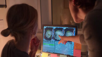 Emily Jacobs and Caitlin Taylor look at images of the brain on a computer.