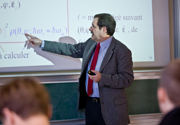 Alain Aspect bir projektör ekranında bir denklemi işaret ediyor