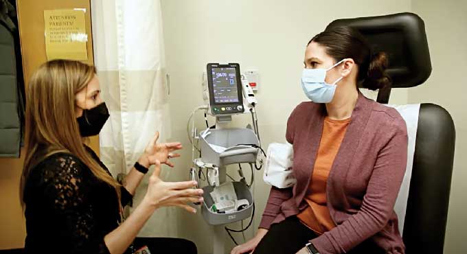 A female doctor (left) speaks with a female patient (right)