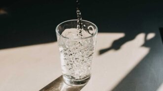 A photo shows water, a possible source of PFAS exposure, pouring into a glass.