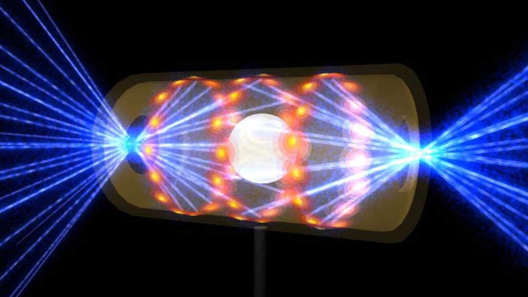 an illustration of a nuclear fusion experiment showing dozens of blue laser beams pointing at a capsule-shaped object with three red rings inside, and a white orb at the center