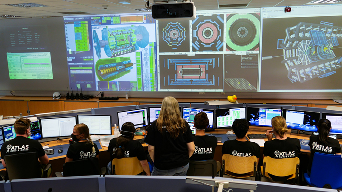 A group of researchers watch from a control room as the Large Hadron Collider at the CERN lab.