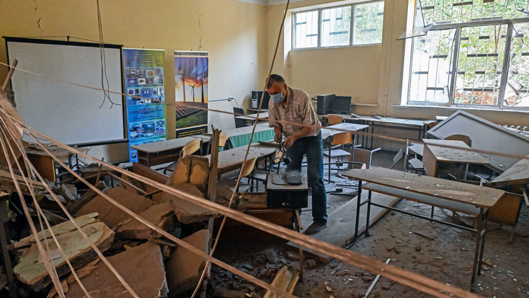 A Kharkiv Polytechnic Institute staff member sifts through the debris of a classroom destroyed by a Russian missile