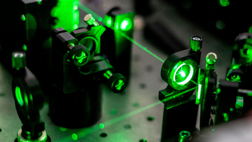 A green laser beam travels through a lens and creates a 90 degree turn