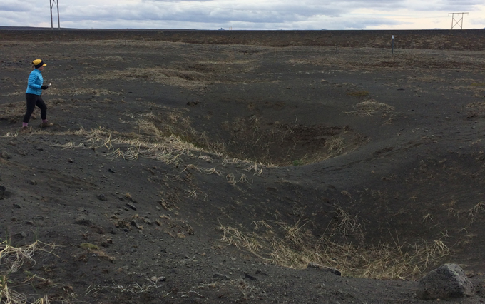 Een persoon loopt in de buurt van kraters in de mijnketen in IJsland.