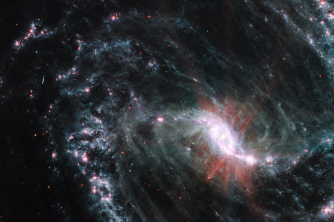 Los astrónomos están utilizando JWST para estudiar varias galaxias con diferentes tipos de estructuras espirales para comparar cómo se forman sus estrellas. NGC 1365 (en la imagen) tiene una barra brillante en su núcleo que conecta sus brazos espirales. JWST detectó polvo brillante en el centro de esta galaxia que había sido oscurecido en observaciones anteriores.