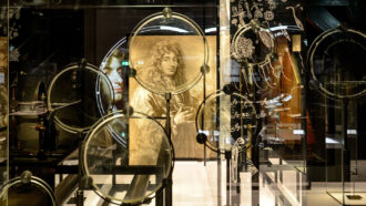 A collection of lens set up in front of a drawn portrait of Christiaan Huygens.